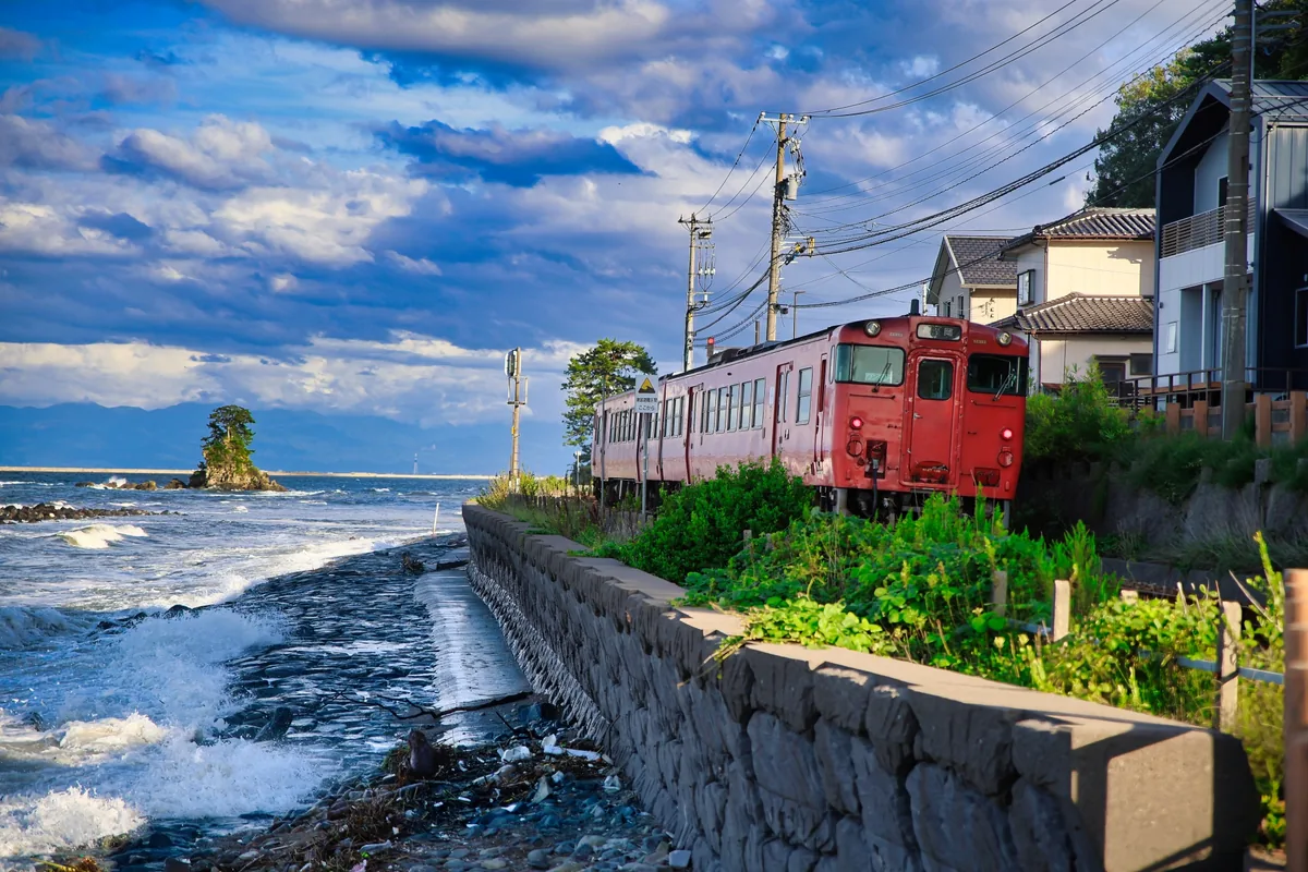 雨晴海岸の海沿いを走る列車と女岩（富山県）
