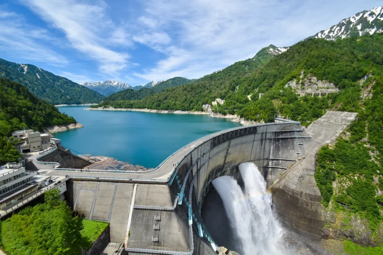 観光放水を行う黒部ダムの堤体と黒部湖（富山県）